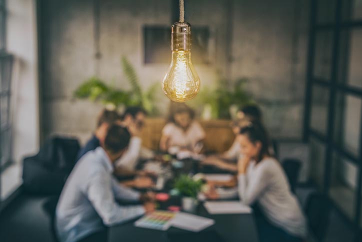 People working together around a desk. Systems thinking, types of systems thinking.